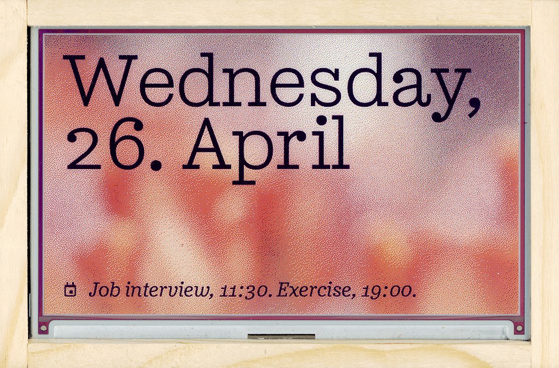 E-ink display in wooden frame displaying the current date with some agenda items for the same day.