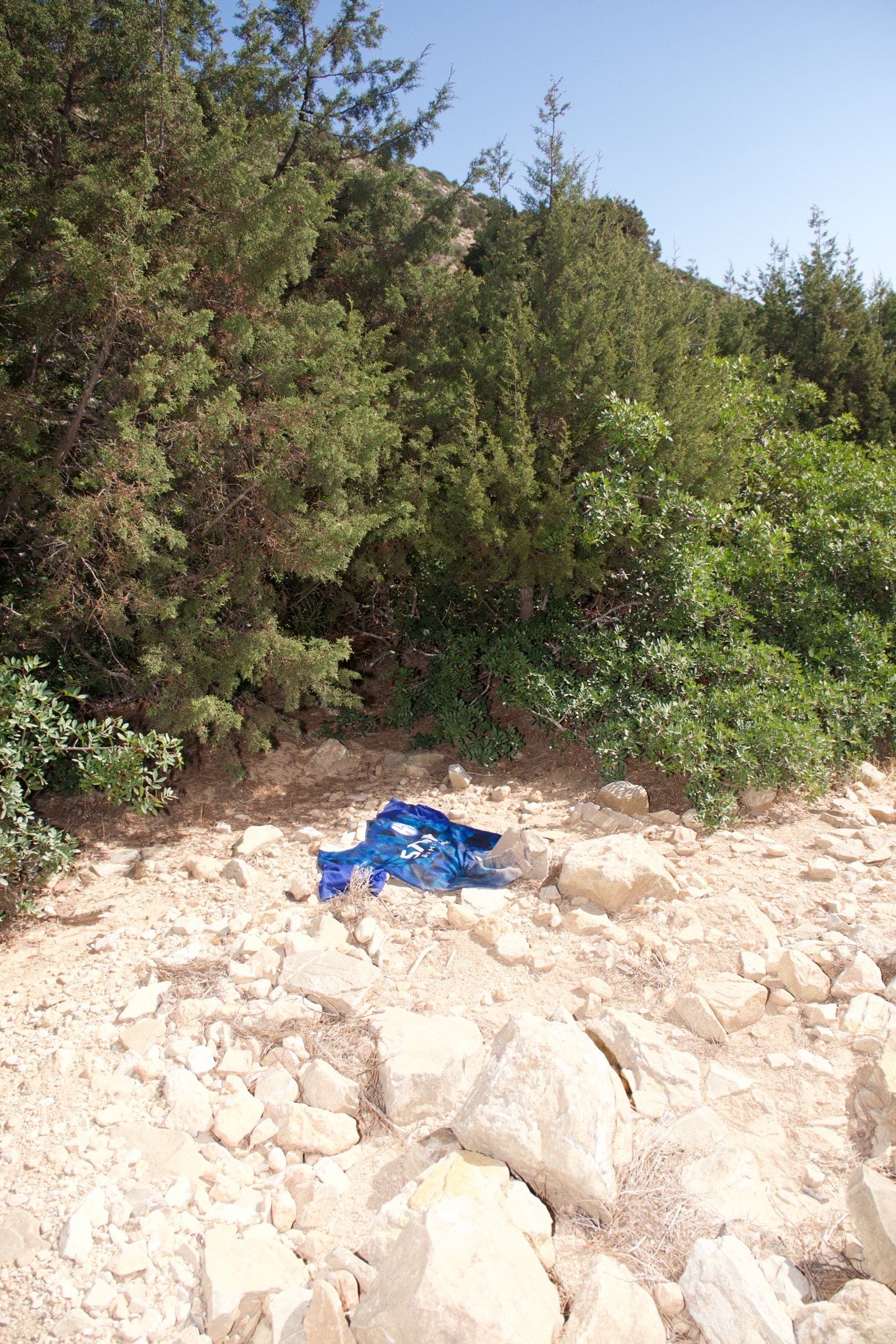 Today, Hank and I took the path of Plagia.  We found a farmer who gave us a ride in the back of his truck down to Lia, a small coastal area with just five houses and two closed tavernas. From Lia, we took a dirt path on foot.  As we walked, I kept spotting pieces of clothing tangled in the trees and thorny bushes along the trail. It was an incredibly eerie landscape. The air felt suﬀocatingly heavy. You could palpably feel the recent presence of people—people exactly like you—sweating and pushing through this exact brush, yet there was absolutely no one in sight.
