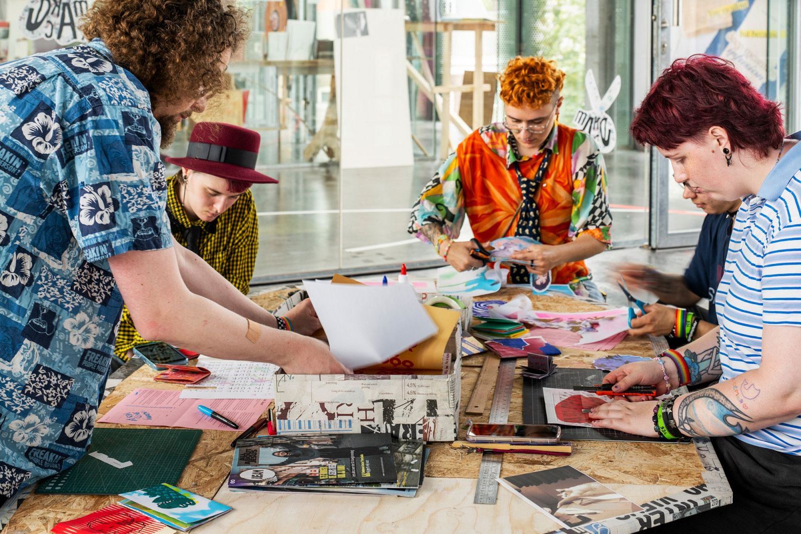 close-up of the people sitting around the table, making zines